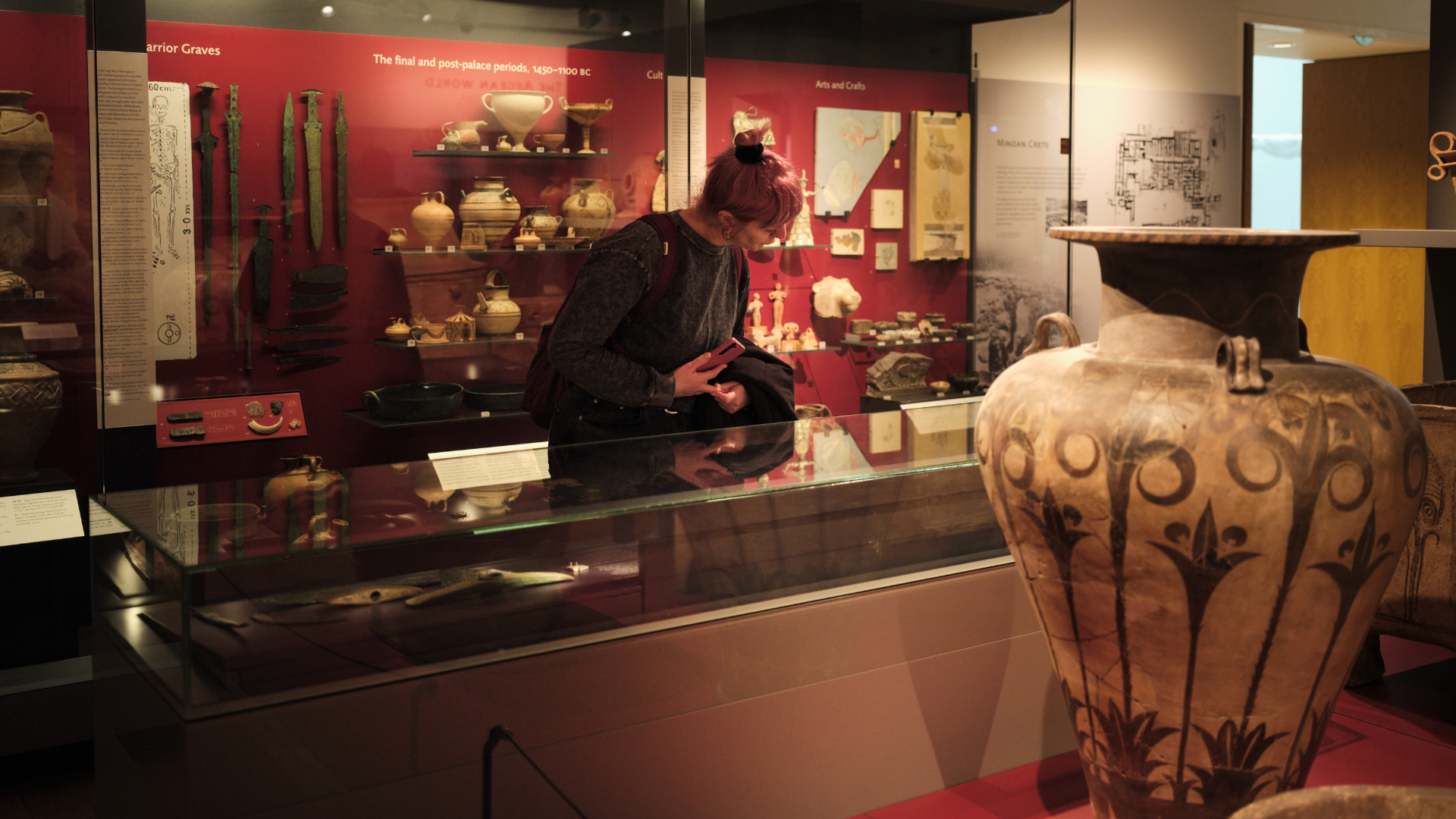 An adult learner in a museum art gallery, looking at ancient artefacts in display cases.