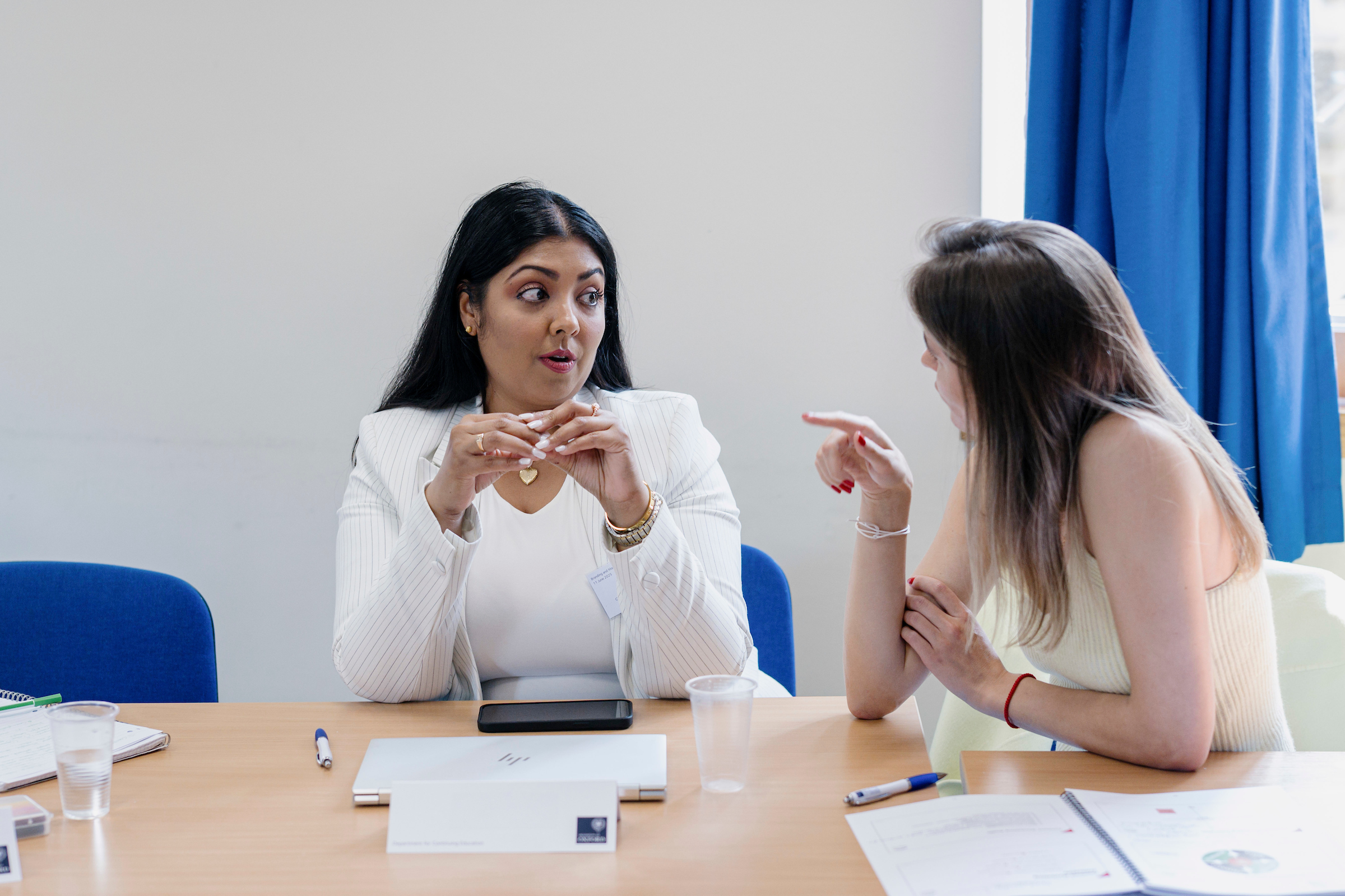 Two women sit at a table in discussion