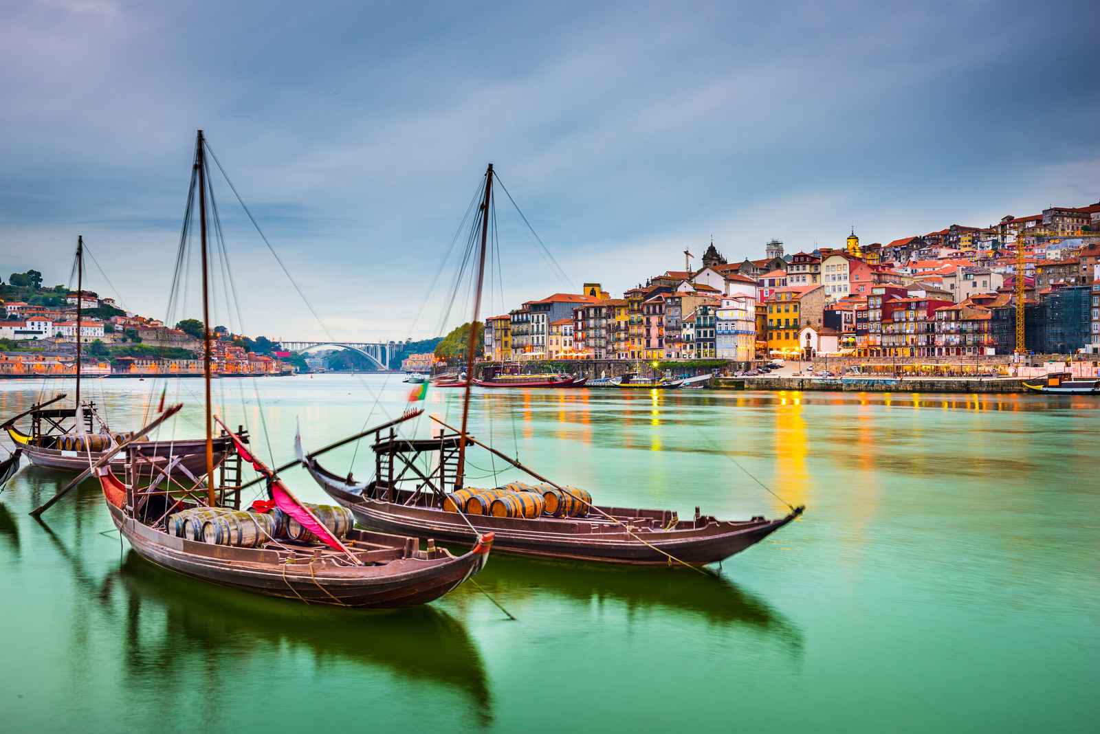 Two sailing boats on a lake with colourful beachfront houses in the background.