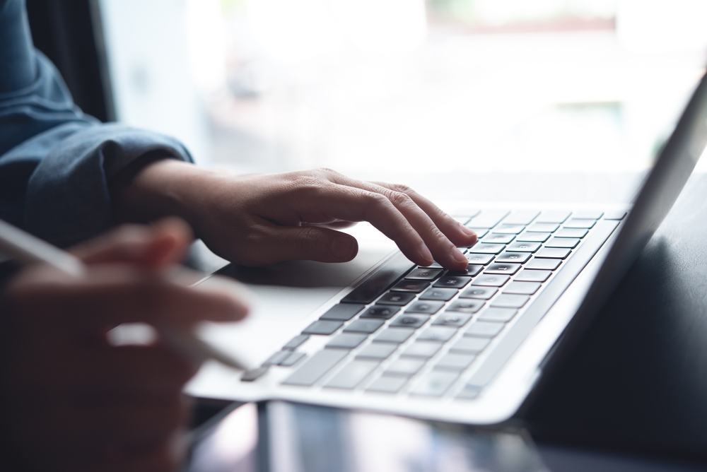 View of male hands typing on a laptop.