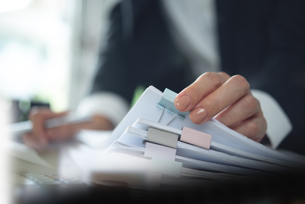 Person working with a stack of paper corporate files.