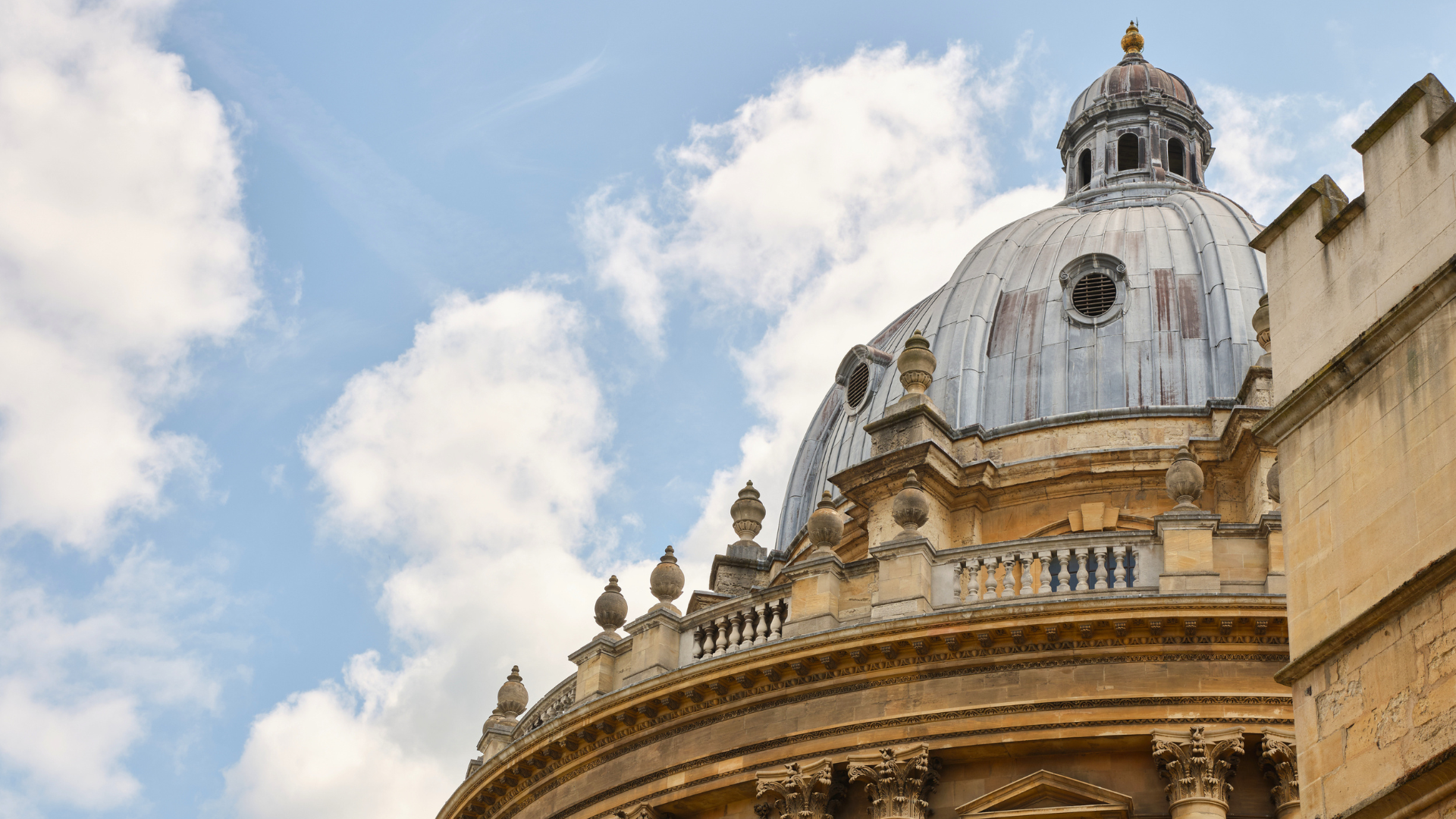 The Radcliffe Camera rooftop with another old building with turrets to the right.