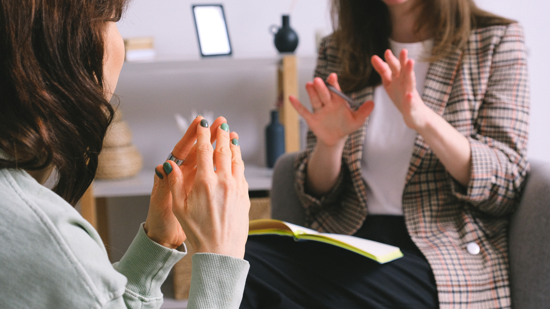 A counsellor in conversation with a patient, only shown from the shoulders down.