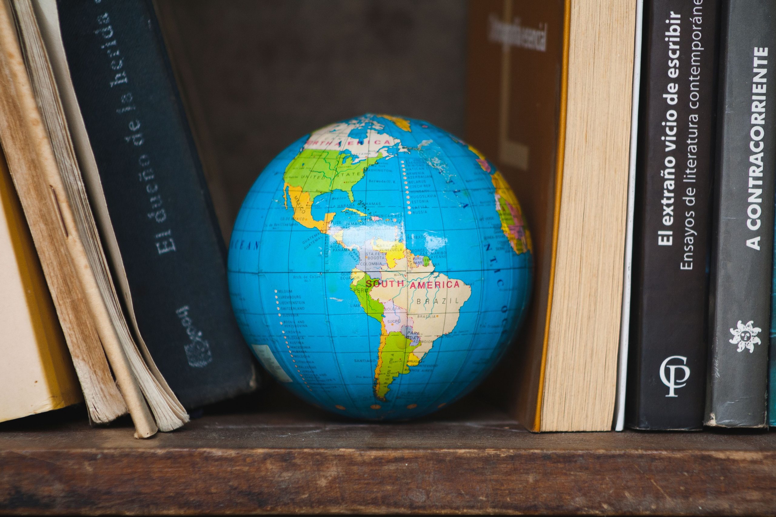 A globe sitting on a bookshelf.